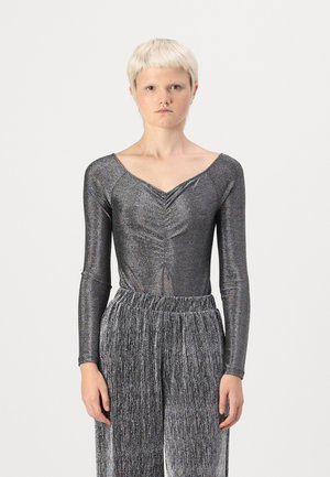 Shiny, long-sleeve bodysuit in dark gray with a v-neck and gathered detail. Paired with flared, pleated silver pants featuring a stretchy waistband.