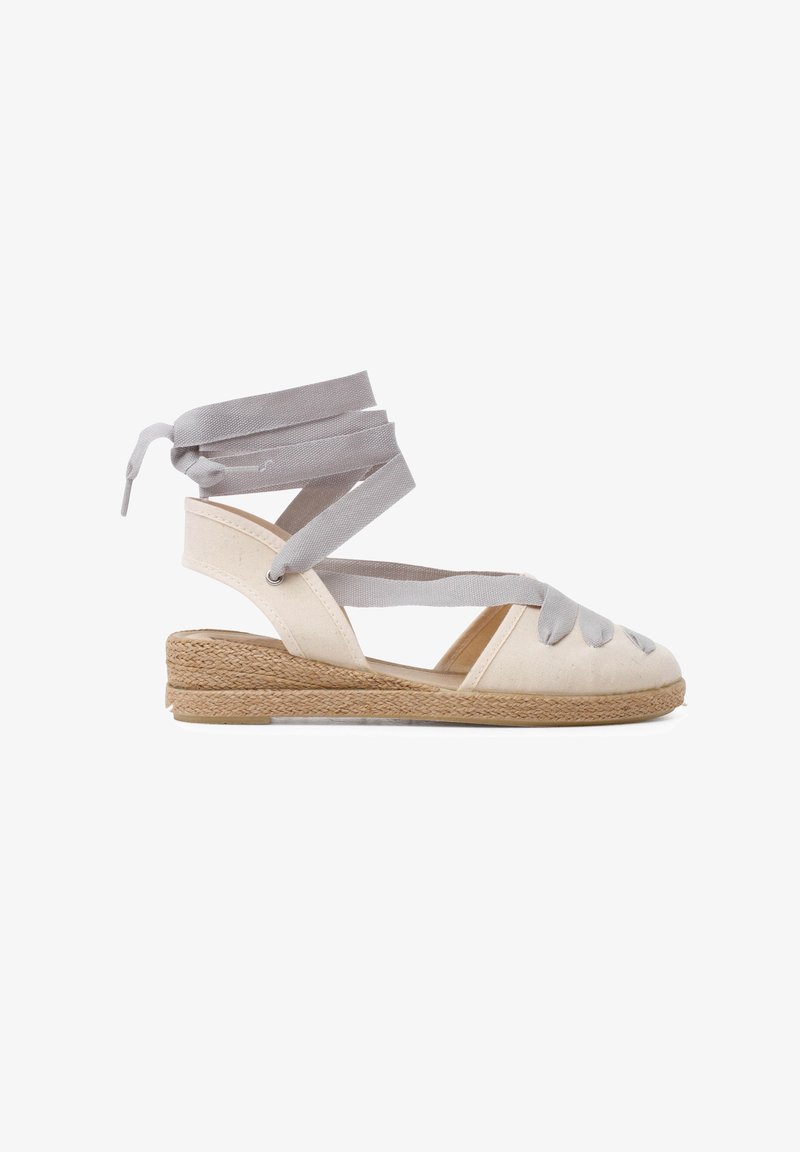Sandale espadrille avec une tige en toile beige, des liens grisés et un talon en jute. Design à bout ouvert avec des détails entrecroisés.