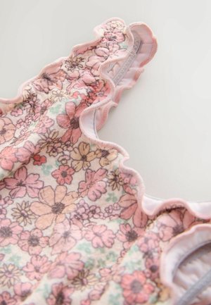 Floraler Stoff in sanften Pastellfarben mit wellenförmigem Rand; zeigt rosa und orange Blumen auf hellem Hintergrund, mit glatter Textur.