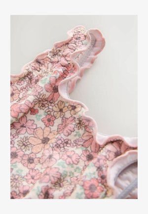 Blommönstrat tyg i mjuka pastellfärger med en vågig kant; innehåller rosa och orange blommor på en ljus bakgrund, med en mjuk textur.