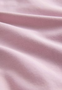 Meka, svijetlo ljubičasta tkanina s finom teksturom i nježnim naborima koji stvaraju suptilne sjene i istaknute dijelove.