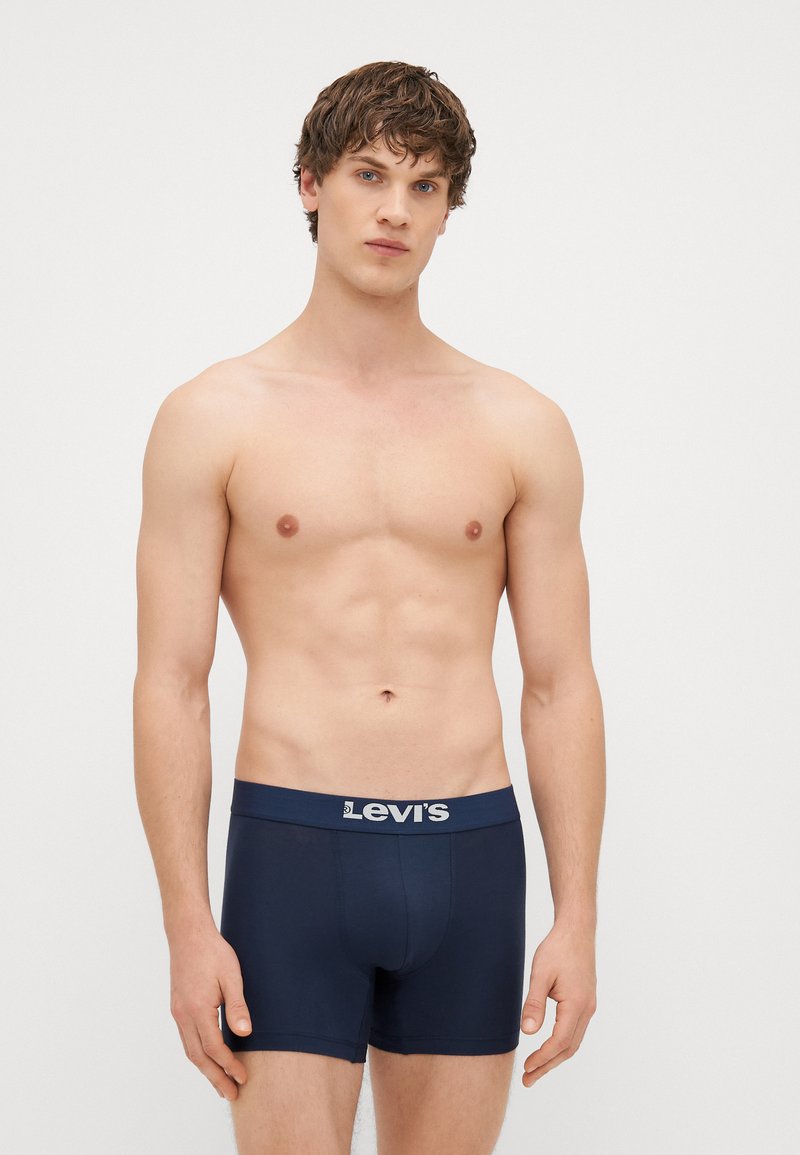 Navy cotton boxers with a logo-embellished waistband, featuring a snug fit and smooth texture, displayed on a person with an athletic build.