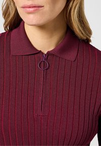 Bordowa prążkowana koszulka polo z zamkiem do ćwiartki i okrągłym suwakiem. Posiada teksturowaną tkaninę i dopasowany krój.