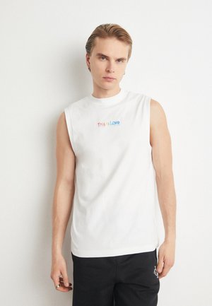 Camiseta sin mangas de algodón blanca con el texto "Esto es Amor" en colores del arcoíris, con un cuello redondo y corte relajado.