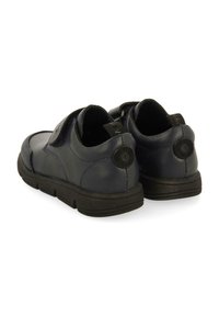 Chaussures en cuir bleu marine avec une finition texturée, forme arrondie et une bande velcro ; elles disposent d'une semelle en caoutchouc noire et d'accents de logo.