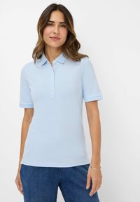 Lyseblå polo-shirt med korte ærmer, detaljeret med knapper og krave, lavet af blødt materiale. Enkel og tætsiddende design.
