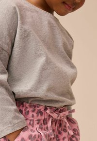 Grå långärmad topp kombinerad med rosa djurmönstrade shorts med elastisk midja och knytdetalj. Mjuk, avslappnad tyg med ledig passform.