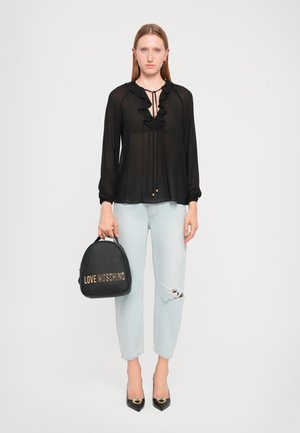 Black sheer blouse with ruffles, light blue distressed jeans, and a black handbag featuring gold "LOVE MOSCHINO" logo. Pointed toe black heels.