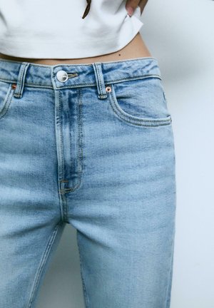 Helles blaues, hoch tailliertes Jeans aus Denim, mit klassischem Fünf-Taschen-Design, Messingknopf und dezentem Verblassen des Stoffes.