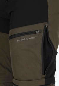 Olijfgroene en zwarte broek met een ritssluiting zak op de bovenbeen, met een gladde textuur en "SWEDEMOUNT" branding in lichtgrijs.