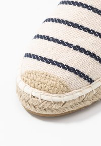 Randig espadrillo i ljusbeige canvas med marinblå linjer, jute-sula och flätade detaljer längs kanten. Rund tådesign.