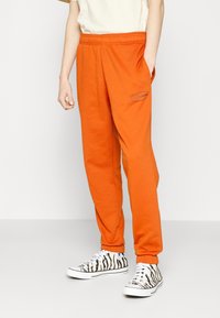 Orange joggers med elastiskt midjeband, sidofickor och en "new balance" logotyp. Matchade med svartvita sneakers med zebramönster.