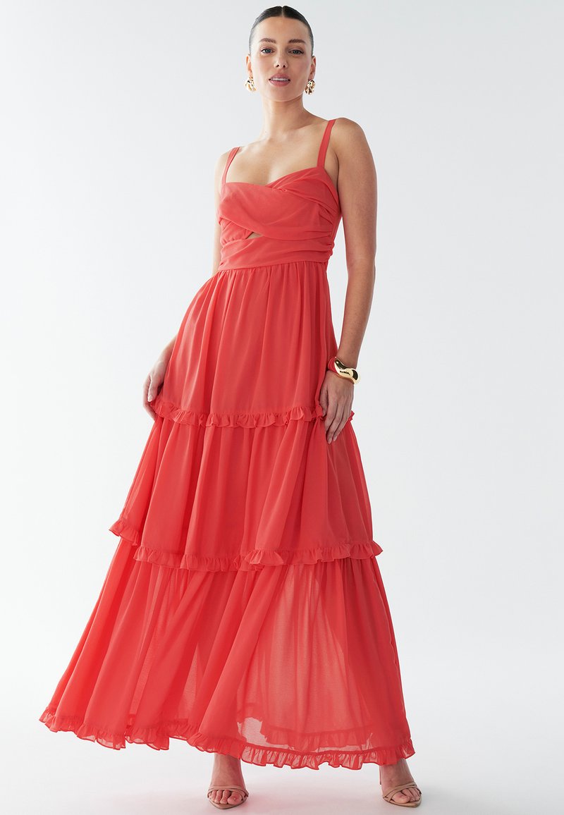 Robe maxi rouge à étages avec bretelles spaghetti, dotée d'un corsage ajusté et d'un ourlet à volants. Confectionnée en tissu transparent et léger.