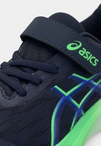 Marine idrettssko med teksturert overdel, grønne og blå detaljer, og en sikker klemmestropp. Har en grønn såle for grep og støtte.