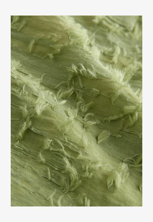 Hele roheline tekstuuriga kangas, mille servad on narmendavad, näidates kihte ja erinevusi paksuses. Pehme, voolav materjal õrna läikega.