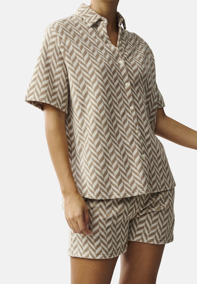Short-sleeve, button-up pajama set in beige with a herringbone pattern. Made of soft fabric with a relaxed fit and matching shorts.