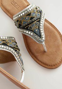 Infradito con perline e suola in pelle marrone. La parte superiore presenta intricati motivi con perline blu, oro e argento con riflessi.