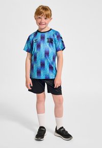 Blå och lila mönstrad sporttröja med korta ärmar, kombinerad med svarta shorts. Vita strumpor och svarta träningsskor fulländar outfiten.