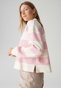 Gestreepte trui van zachte stof met afwisselend lichtroze en witte strepen, een relaxte pasvorm en zijsplitten aan de zoom voor extra comfort.