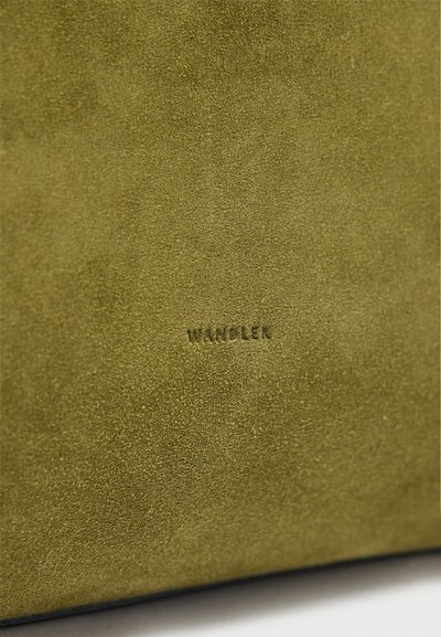 Επιφάνεια από πράσινο ελαστικό σουέτ με μικρό, ανάγλυφο κείμενο "VANDLER" τοποθετημένο κεντρικά κοντά στην κάτω άκρη.