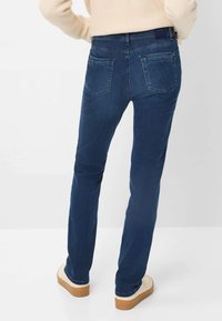Jeans in denim di colore blu scuro con una classica vestibilità a gamba dritta, dotati di due tasche posteriori, un leggero effetto di usura e un girovita di altezza media.