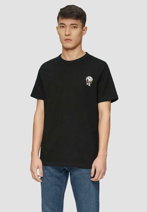 Zwarte katoenen t-shirt met een ronde halslijn, korte mouwen en een kleine cartoonafbeelding op de linkerborst. Draagt het met een blauwe spijkerbroek.