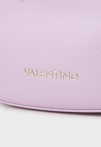 Violetinės tekstūruotos rankinės, pagamintos iš sintetinio audinio, priekyje esančio metalinio auksinio logo "VALENTINO". Lygi, struktūruota forma.