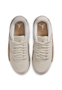 Jasno beżowe sneakersy o zamszowej teksturze, okrągłe sznurówki i gumowa podeszwa. Na języku i wkładce znajduje się złote logo Jordana.