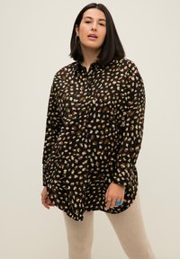 Camicia nera con bottoni e motivo a stampa leopardata nei colori marrone, crema e azzurro chiaro. Presenta un colletto e una tasca frontale, mostrata non infilata.