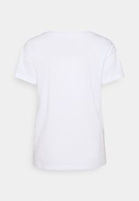 Płaska, biała, krótko rękawowa bawełniana koszulka wyeksponowana z tyłu, z okrągłym dekoltem i luźnym krojem.