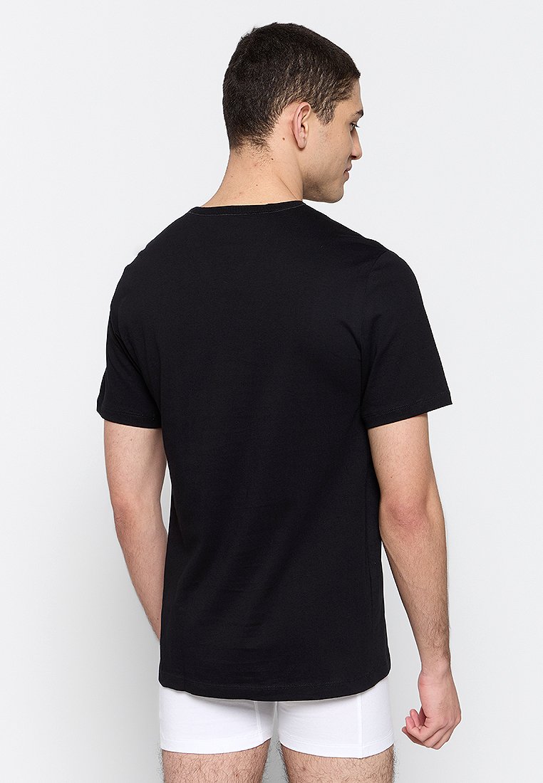 Camiseta de algodón negra con mangas cortas, cuello redondo y un diseño trasero liso. Sin patrones prominentes ni detalles de hardware.