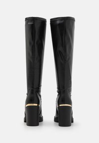 Black leather knee-high boots with a block heel, featuring a gold accent on the heel and vertical stitching details along the shaft.