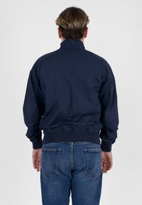 Giacca a vento blu navy con colletto alto, polsini ed elastico in vita. Presenta una texture liscia e leggera e una vestibilità comoda.