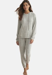 Ensemble de détente gris clair comprenant un haut à capuche avec cordons de serrage et un pantalon assorti. Texture douce avec un motif tacheté. Coupe décontractée.