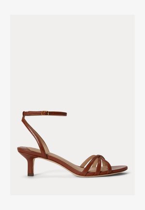 Brązowy skórzany sandał na niskim obcasie z trzema paskami z przodu i regulowanym paskiem wokół kostki z złotą klamrą.