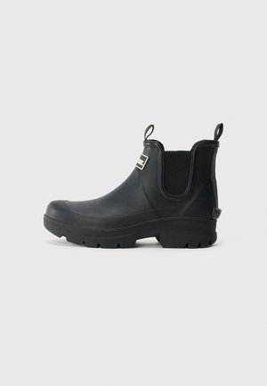 Black waterproof ankle boot with thick lug sole, elastic side panels, pull tabs, and a rectangular logo on the upper front.