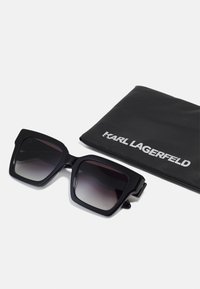 Black oversized sunglasses with a geometric frame and gradient lenses, accompanied by a black soft case featuring the Karl Lagerfeld logo.