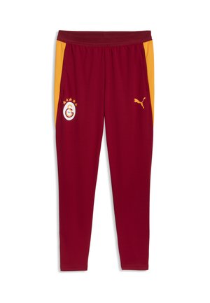 Vinrøde træningsbukser med gule sidelommer, elastisk linning, Puma-logo på højre ben og Galatasaray fodboldklubs emblemer på venstre ben.