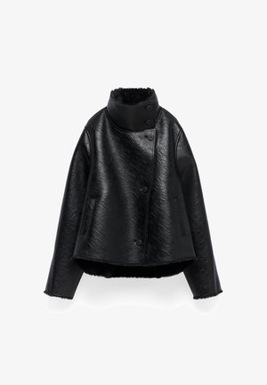Giubbotto di pelle nera con colletto alto, quattro bottoni e due tasche laterali. Texture liscia con orlo leggermente accorciato e foderato in pile.