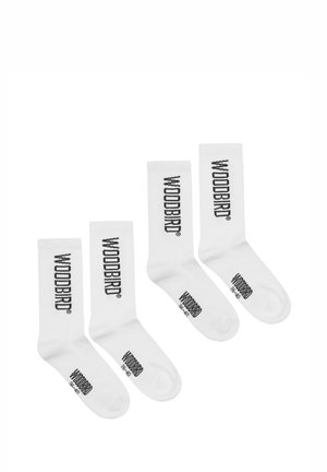 Vier weiße Socken mit dem schwarzen Schriftzug "WOODBIRD", der vertikal und horizontal aufgedruckt ist, auf einem weißen Hintergrund in aufsteigender Größenordnung angeordnet.