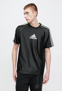 Μαύρο αθλητικό T-shirt με γυαλιστερό φινίρισμα, με λευκό λογότυπο Adidas και τρεις λευκές ρίγες στους ώμους, κοντά μανίκια.