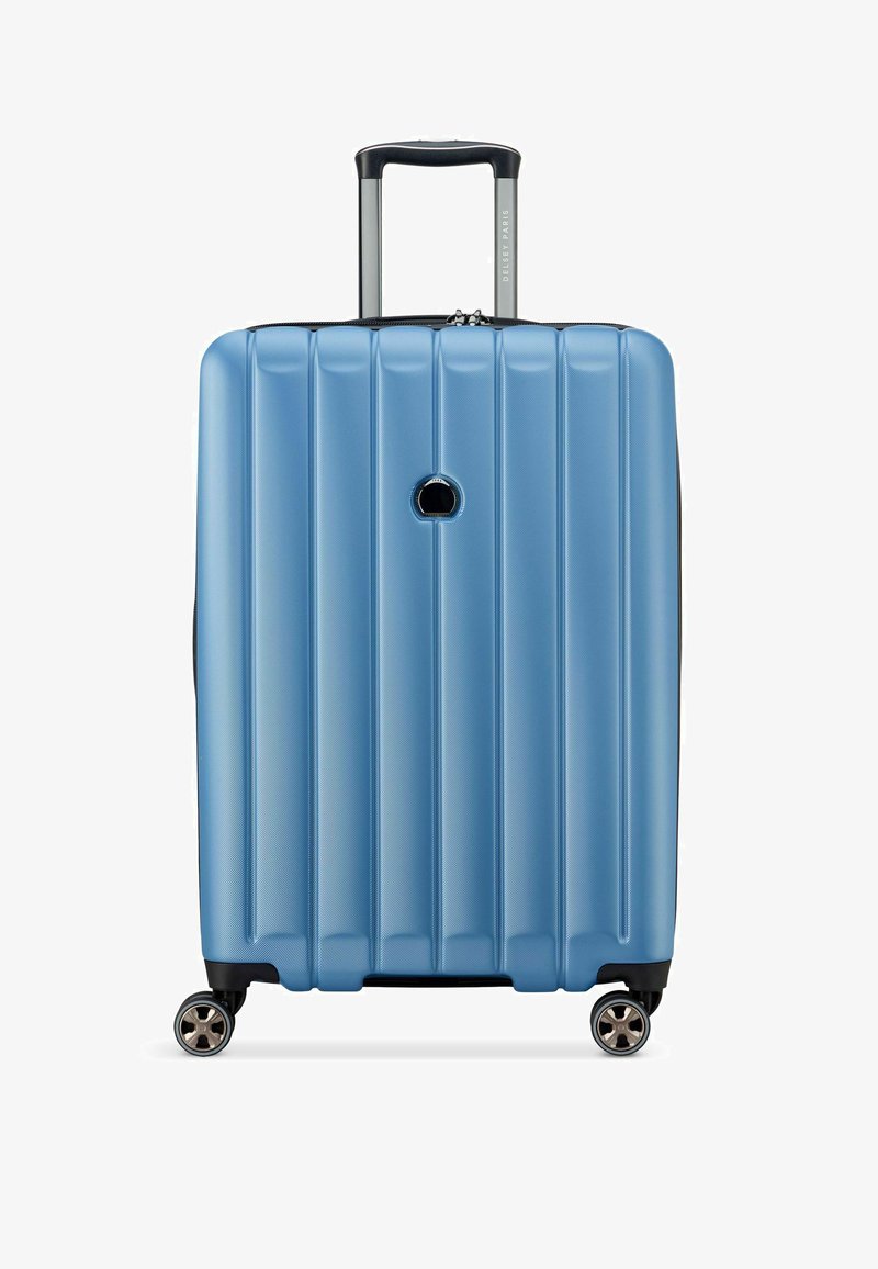 Valise rigide bleue avec des rainures verticales, poignée télescopique et quatre roues pivotantes pour une maniabilité facile.