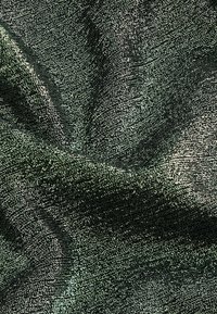Texturerat grönt tyg med en skimrande yta och ett prickigt mönster, som visar mjuka veck och en reflekterande kvalitet.