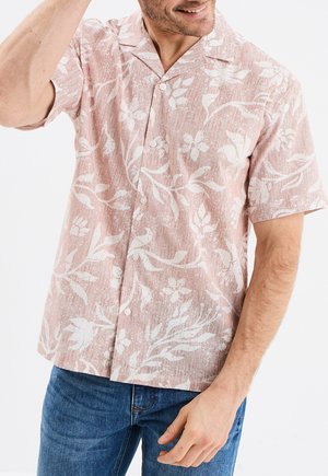 Camisa de botones de manga corta en rosa claro con patrones florales blancos y un acabado texturizado. Presenta un cuello clásico y botones en la parte delantera.