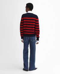 Navy- und rotgestreifter Strickpullover, mit Rundhalsausschnitt und lässiger Passform. Kombiniert mit weit geschnittenen blauen Jeans, die Gesäßtaschen und einen weit auslaufenden Saum zeigen.