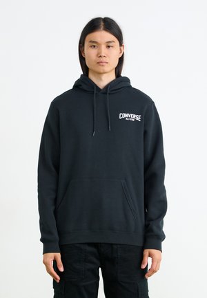 Sudadera negra con bolsillo frontal, capucha ajustable con cordón y el logotipo blanco "Converse All-Star" en el área del pecho izquierdo. Material de algodón.
