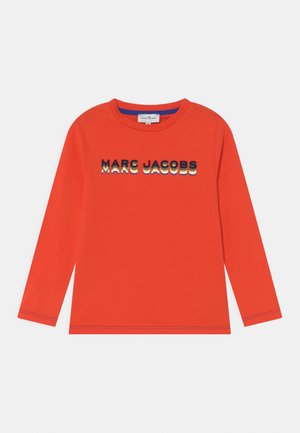 Lyse orange langærmet skjorte med "MARC JACOBS" tekst i lagdelte sorte, hvide og gule bogstaver over brystet.