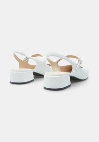 Valged slingback-jalatsid sujuva nahkplateeringuga, ümmarguse nina ja ploki kontsaga. Sobilikult must aktsent kontsa alusel.