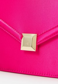 Roze satijnen clutch met een gladde textuur, voorzien van een gouden vierkante gesp en gestikte accenten langs de randen.