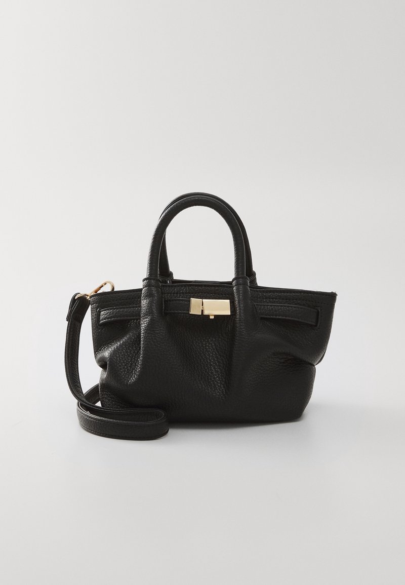 Sac à main en cuir noir texturé avec deux poignées courtes, une longue bandoulière et une boucle rectangulaire dorée sur un fond clair uni.